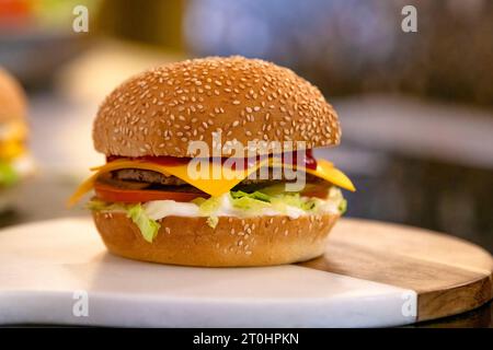 Delicious grilled burgers. Delicious fresh cheeseburger with old grey background. Fresh American kitchen. Close-up of home made burger. Stock Photo