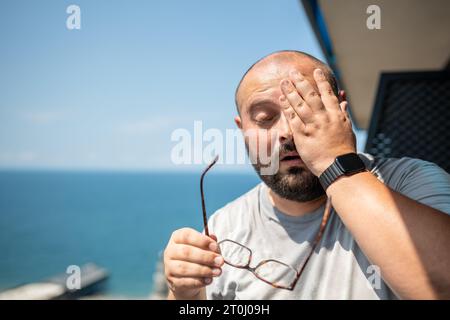 Bald fat man drenched in sweat wiped off excess moisture. Sweating, high temperature, overweight Stock Photo