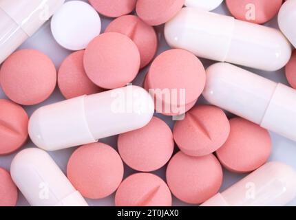 Many pink and white pills and capsules. Medical treatment with medicine, vitamins or nutrition supplements in tablets and capsules. Woman health. Text Stock Photo