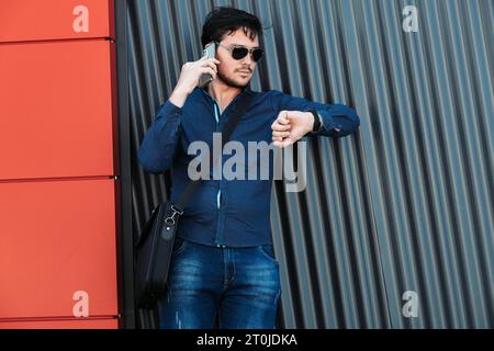 Young corporate businessman in casual wear looking at his wristwatch Stock Photo
