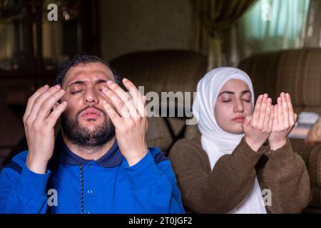 muslim couples praying together asking allah for mercy and forgiveness ,wearing casual clothes in home Stock Photo