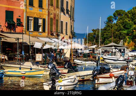 Fishing boats moored in Portofino Italy in the summer with outdoor dining, fresh fish, and the Mediterranean diet for a healthy lifestyle; vacation Stock Photo