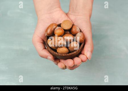 Holding a bowl of nuts, mix variety of almonds, hazelnuts and pecan nuts, healthy food and lifestyle Stock Photo
