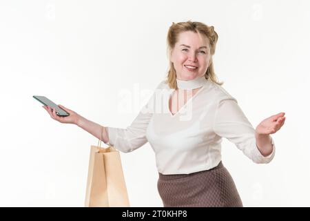 Waist up photo of happy woman with shopping paper package bags and mobile phone. Caucasian ethnicity blonde female 49 years old smiling and looking Stock Photo