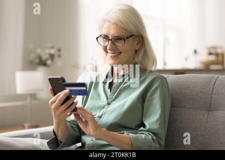 Cheerful blonde older woman using financial bank application on smartphone Stock Photo