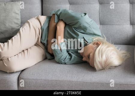 Upset exhausted older woman suffering from strong pain Stock Photo