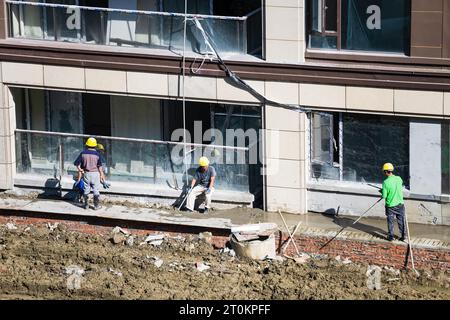 Some workers are resting while others are still working on building the house on a sunny day. Stock Photo