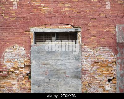 Boarded-up window on a red brick wall Stock Photo