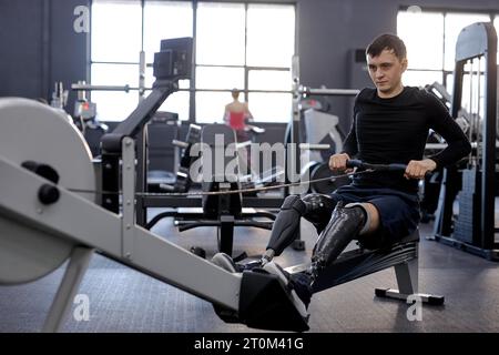 strong man concentrated on pilling rowing machine, side view shot. total-body fitness Stock Photo