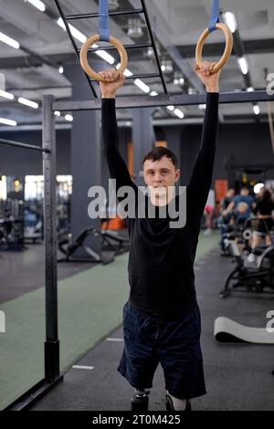 love of life. tired sweaty man holding gymnastic rings, looking at the camera, tiredness, man keeps fit, exhausted sportsman after hanging on rings Stock Photo