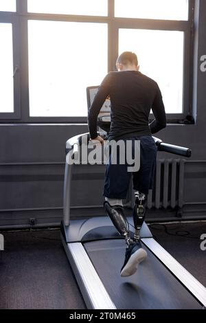 back shot of man with artificial legs running on treadmills at gym, free time, spare time, daily routine wellness. rehabilitation center, practicing. Stock Photo