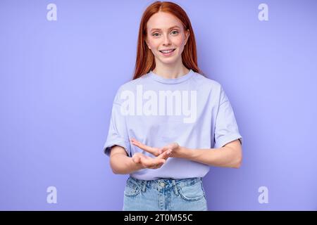 Young deaf red-haired redhead mute woman wants to show book, saying excuse me, sorry close up portrait isolated blue background Stock Photo