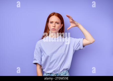 serious unhappy frowning readhead woman in casual clothes with raised palm demonstrating no gest, close up portrait studio shot Stock Photo