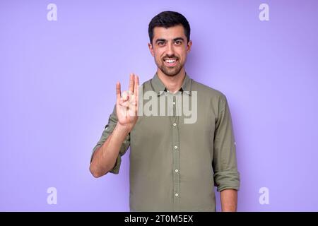 happy handsome smiling deaf mute man using sign language on blue background Stock Photo