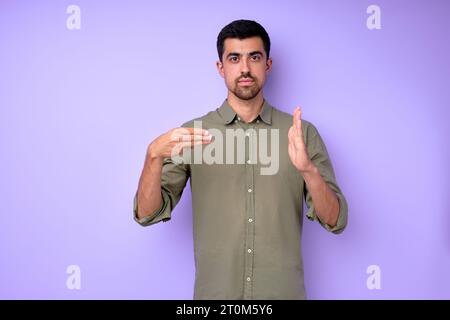 Young serious bearded deaf mute man showing number 300 using sign language on blue background isolated close up portrait Stock Photo