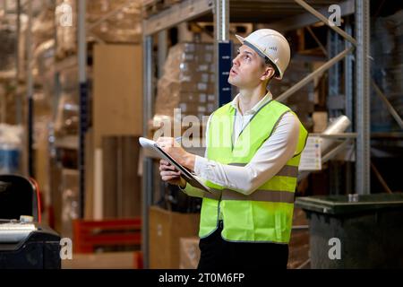 confident male worker doing stocktaking of product management on shelves in warehouse, counting and taking notes. Physical inventory count. Male profe Stock Photo