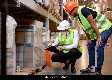 Manager and supervisor taking inventory in warehouse, male workers in uniform talking, discussing, good job teamwork. confident and concentrated guys Stock Photo