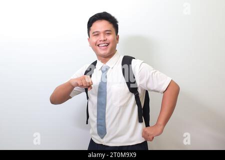 Indonesian senior high school student wearing white shirt uniform with gray tie showing making fun and dancing gesture with hands. Isolated image on w Stock Photo