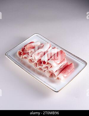 fresh and aesthethic bacon rolls on a white plate. View from above. Chinese cuisine, ingredient for hotpot Stock Photo