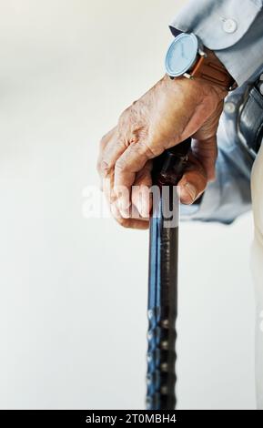 Elderly, person and hand with walking stick in closeup for assistance, walk or health in nursing home. Wrinkles, fingers and hold on blurred Stock Photo