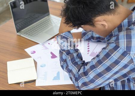 Back view close up of freelance male feeling confused and frustrated while looking down into official document, signing contract and tax. Holding his Stock Photo