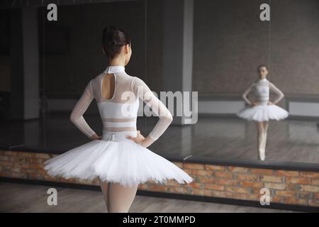 Worried ballerina standing near huge mirror at dance studio Stock Photo