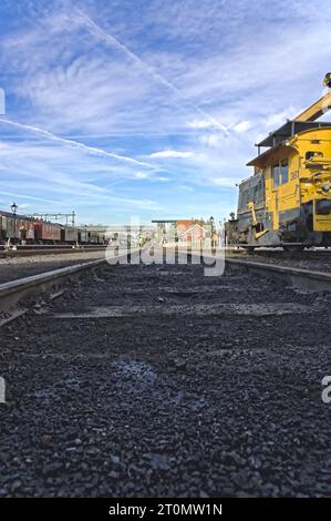 Low angle view museum train track with coal and soot remains. On siding a Diesel-electric Sik crane locomotive and a train with old wagons and people Stock Photo