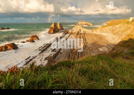 Rainbow over Playa de la Arnia in Santander, Cantabria, North Spain with cliffs and flysch rocks. Popular travel destination Stock Photo