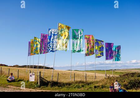 A Conversation Called By The Wind, a public art installation of colourful flags blowing in the wind at Seaford Head Nature Reserve in East Sussex Stock Photo