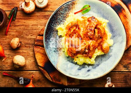 Pieces of stew garnished with mashed potatoes. Meat stew in plate on old wooden table Stock Photo