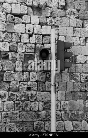 Black and white walking pedestrian crossing light turned green against a brick stone background wall. Communication and safety concept Stock Photo