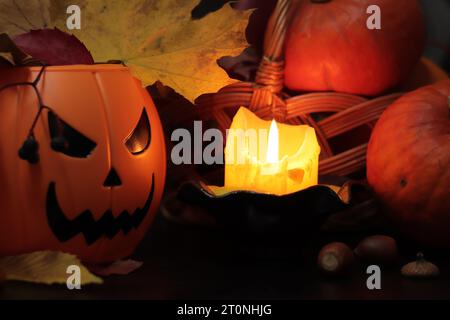 Happy Halloween. A plastic pumpkin bucket with an evil smiling. Halloween horror concept. Ripe pumpkins in a basket in the light of a candle, horror c Stock Photo