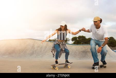 Young couple skillfully riding skateboards on ramp Stock Photo