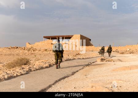 Back view of soldiers of infantry army moving in desert. Sand and blue sky on background of military israel men in fortress. Tired service men with we Stock Photo