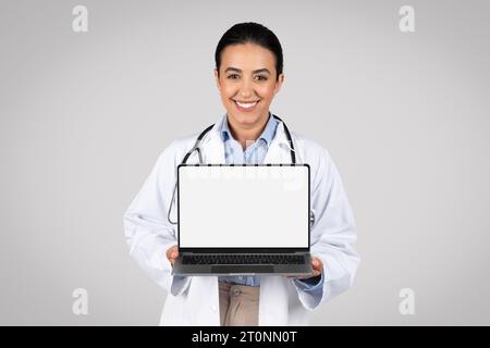 Doctor displaying laptop computer with blank screen for mockup Stock Photo