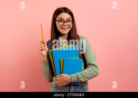 Joyful teen student with backpack and workbooks has a bright idea Stock Photo
