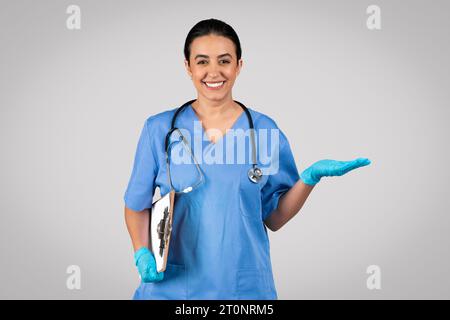 Doctor in blue uniform holds clipboard, presenting something on her palm Stock Photo