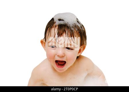 A happy child is playing with toys while sitting in a white homemade bathtub, isolated on white background. Little toddler baby boy bathes in a bubble Stock Photo