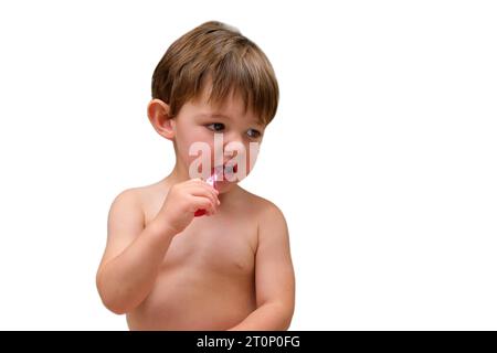 In the bathroom, the baby boy is learning to brush his teeth using a toothbrush, isolated on white background. Kid aged two years (two-year-old boy) Stock Photo