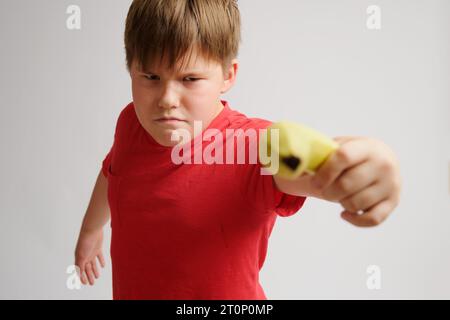 Child boy playing with a yellow banana on a gray background Stock Photo