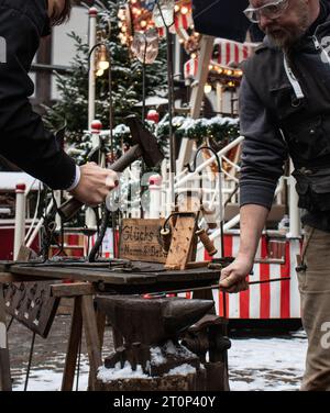 A blacksmith teaching a man his craft on a Christmas fair in Marburg, Germany at 20.12.2018 Stock Photo