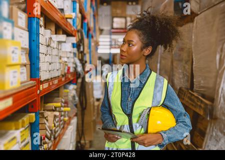Woman teen worker African American black girl employee working in stock shelf warehouse checking inventory storage management staff. Stock Photo