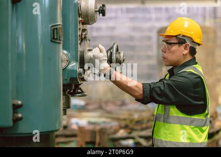 Asian adult engineer male skill worker manual control operate metal lathe milling machine in heavy industry factory Stock Photo