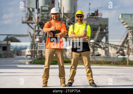 Industrial workers outdoors. Engineers in safety uniform and helmet on factory outdoor. Industrial engineers with factory worker. Factory industrial e Stock Photo