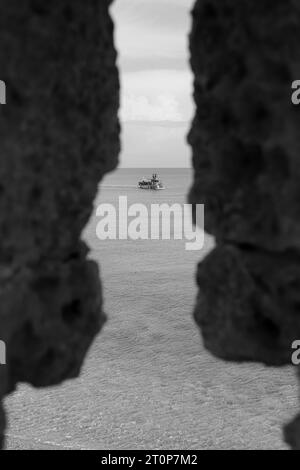 Black and white Poseidon Submarine boat mid tour departing from Mandraki Harbor viewed from a window hole in the city's fortress Stock Photo