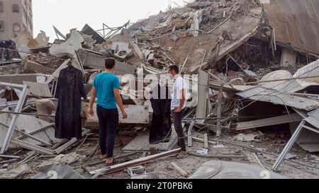 Gaza, Palestine. 8th Oct, 2023. (INT) Palestinians inspect the ruins of the Watan Tower, Palestine Tower, which were destroyed by Israeli air strikes in Gaza City. October 8, 2023. Gaza, Palestine: Palestinians inspect the ruins of the Watan Tower, Palestine Tower, which were destroyed by Israeli air strikes in Gaza City. Fighting raged between Israeli forces and the Palestinian Hamas movement on October 8, as Hundreds of people were killed on both sides after a surprise attack on Israel that prompted Prime Minister Benjamin Netanyahu to warn that they were ''embarking on a long and difficul Stock Photo