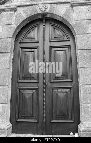 Closeup of a wooden double door with metal hardware at Lindos on Rhodes island, Greece in black and white Stock Photo