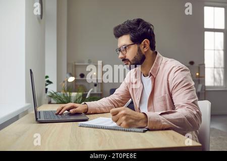 Side view shot of young man wearing glasses using laptop Stock Photo