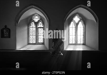 ST.HILARY CHURCH SUNLIGHT STREAMING THROUGH THE WINDOW ILLUMINATING STATUE OF JESUS Stock Photo