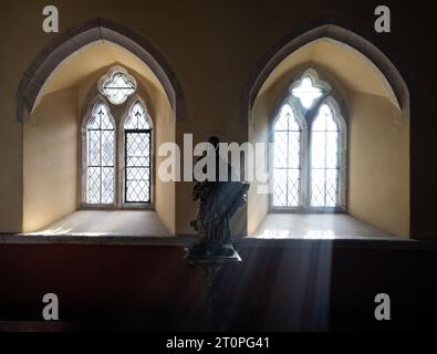 ST.HILARY CHURCH SUNLIGHT STREAMING THROUGH THE WINDOW ILLUMINATING STATUE OF JESUS Stock Photo